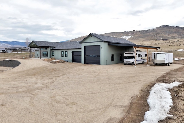 view of front facade featuring driveway, a mountain view, and roof with shingles