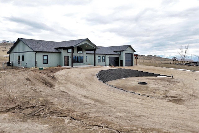 modern farmhouse with an attached garage, driveway, fence, and a shingled roof