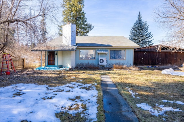 snow covered house featuring ac unit, a chimney, and fence