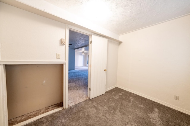 empty room featuring carpet, a textured ceiling, and baseboards