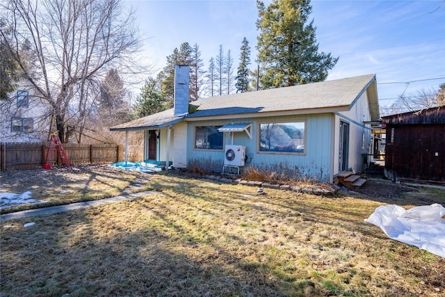 back of property featuring a chimney, fence, and a lawn