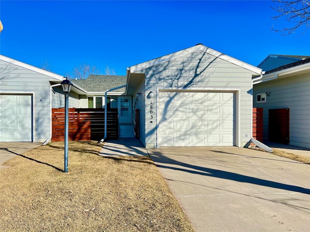 view of property exterior with an attached garage, fence, and concrete driveway