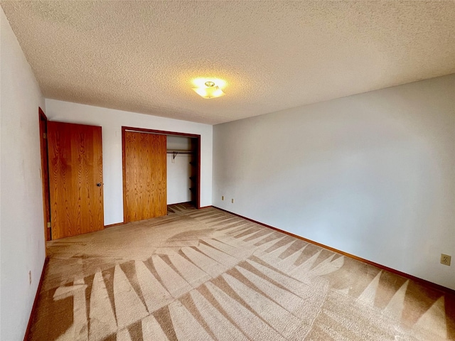 unfurnished bedroom with a closet, carpet flooring, a textured ceiling, and baseboards