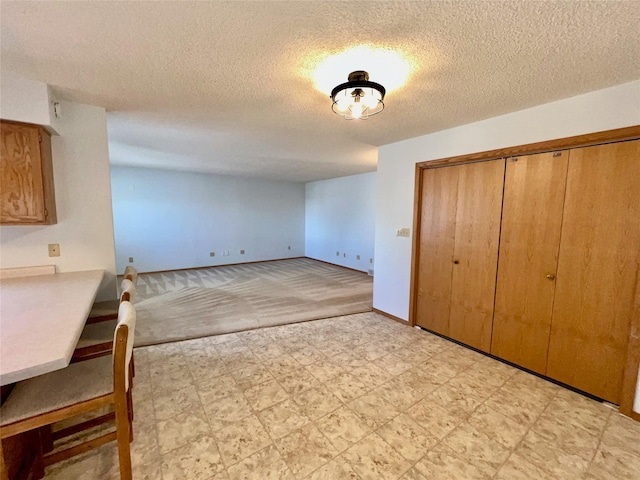 unfurnished dining area with a textured ceiling, light floors, and baseboards