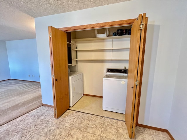 clothes washing area featuring laundry area, a textured ceiling, baseboards, and washer and dryer