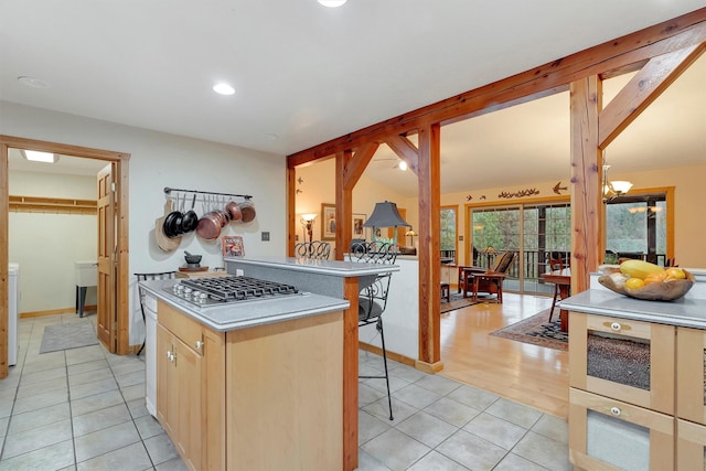 kitchen featuring lofted ceiling, a kitchen island, a kitchen breakfast bar, stainless steel gas stovetop, and light tile patterned flooring