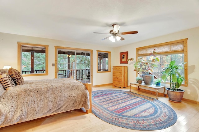 bedroom with access to outside, multiple windows, baseboards, and wood finished floors