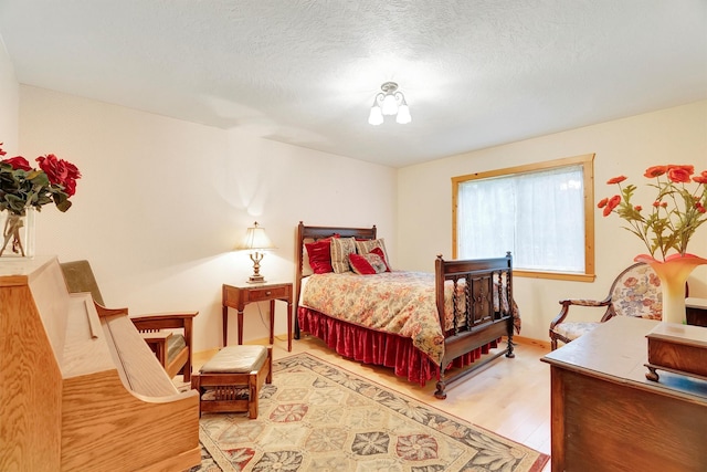 bedroom with a textured ceiling, wood finished floors, and baseboards