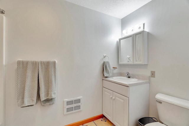 bathroom featuring visible vents, vanity, toilet, and a textured ceiling