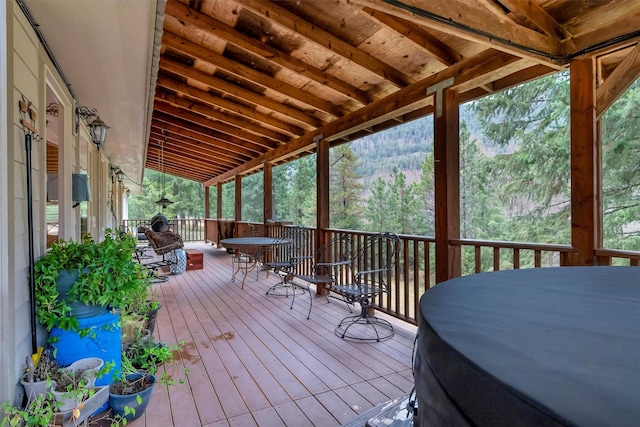 deck featuring a grill, outdoor dining area, and a view of trees