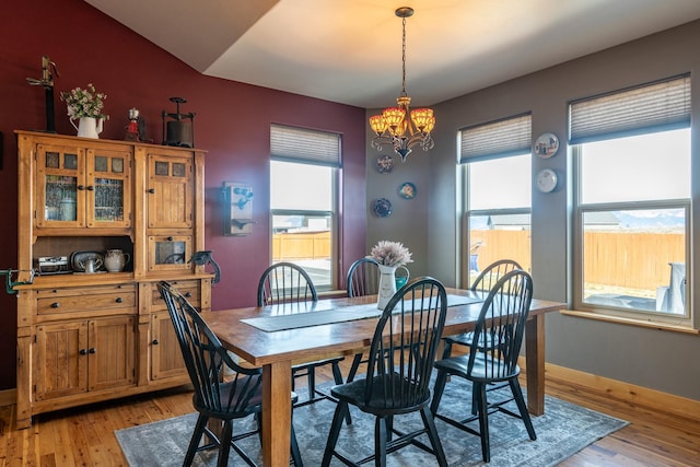 dining space with light wood-style floors, a chandelier, and baseboards