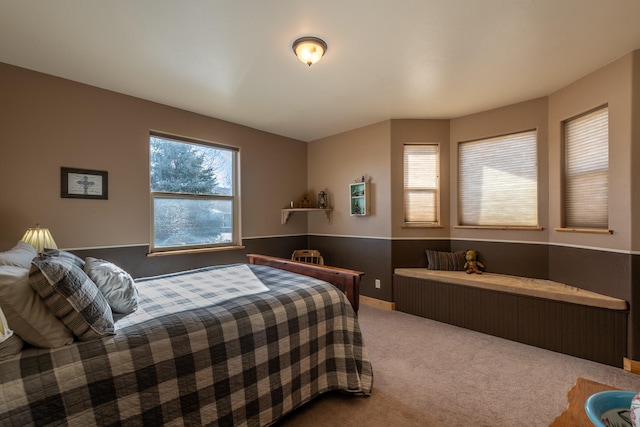 carpeted bedroom featuring a wainscoted wall