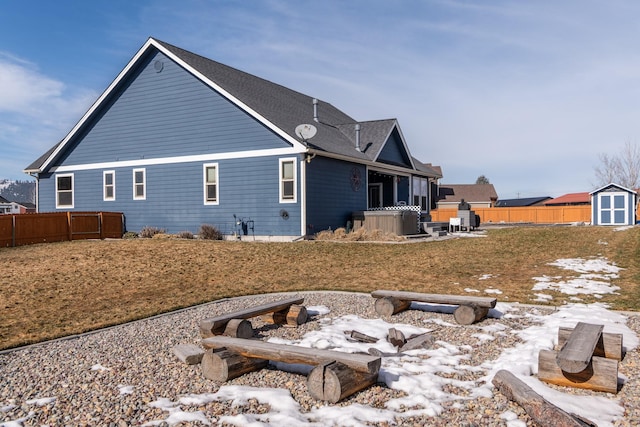 back of property with a storage shed, fence, and an outbuilding