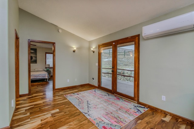 entryway featuring baseboards, lofted ceiling, wood finished floors, french doors, and a wall mounted AC