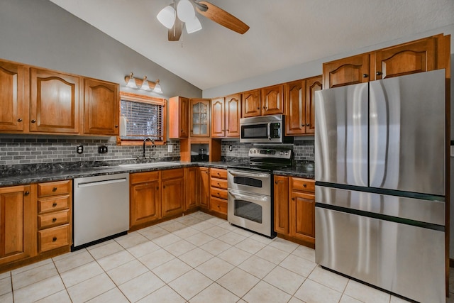 kitchen featuring lofted ceiling, stainless steel appliances, a sink, and brown cabinets