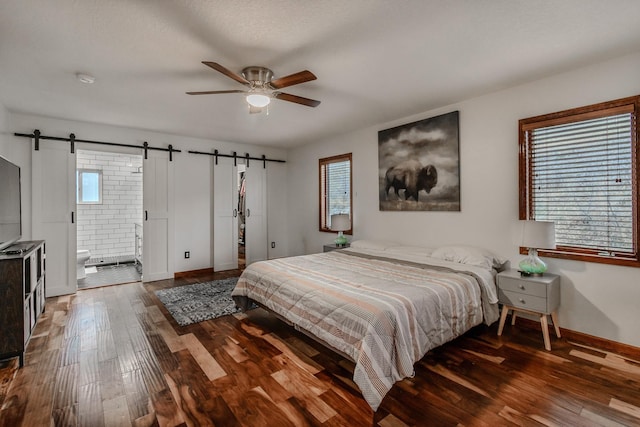 bedroom featuring wood finished floors, connected bathroom, baseboards, and a barn door