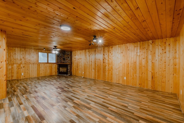 unfurnished living room featuring wood walls, a fireplace, wood finished floors, wood ceiling, and a ceiling fan