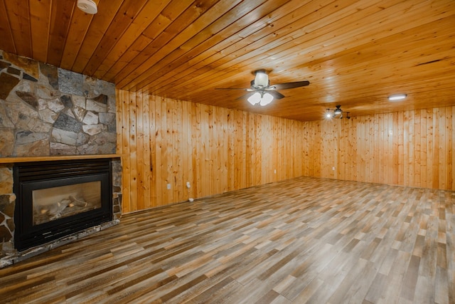 unfurnished living room featuring wooden ceiling, a fireplace, wooden walls, and wood finished floors