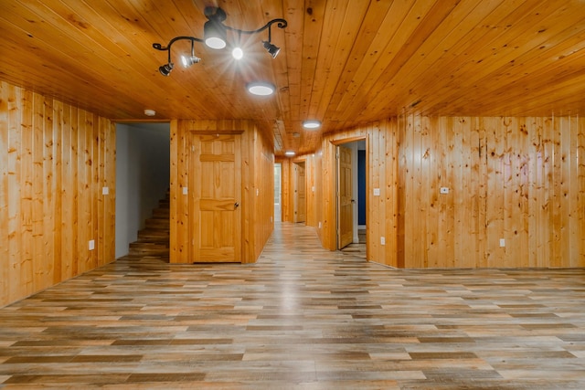 unfurnished room featuring wooden ceiling, stairs, wood finished floors, and wood walls