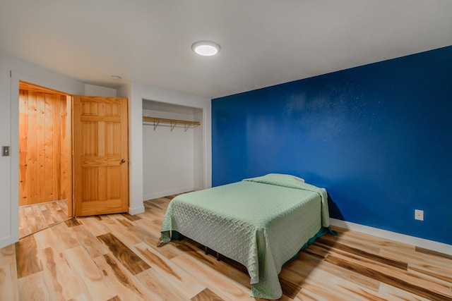 bedroom with a closet, baseboards, and wood finished floors