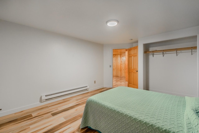 bedroom featuring a baseboard radiator, baseboards, and wood finished floors