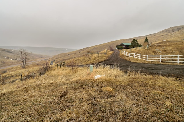 view of yard with fence, a mountain view, and a rural view