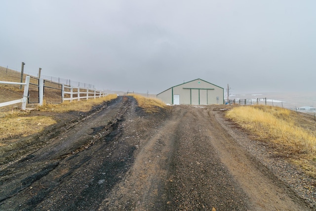 view of road featuring an outbuilding, a rural view, and driveway