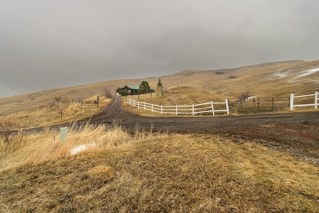 exterior space featuring fence, a mountain view, and a rural view