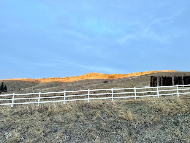 view of yard featuring a rural view, fence, and a mountain view