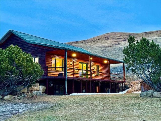 rear view of house with faux log siding, a mountain view, metal roof, and a yard