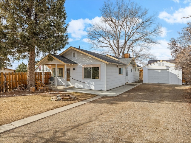 bungalow-style house featuring an outbuilding, a chimney, dirt driveway, a porch, and fence