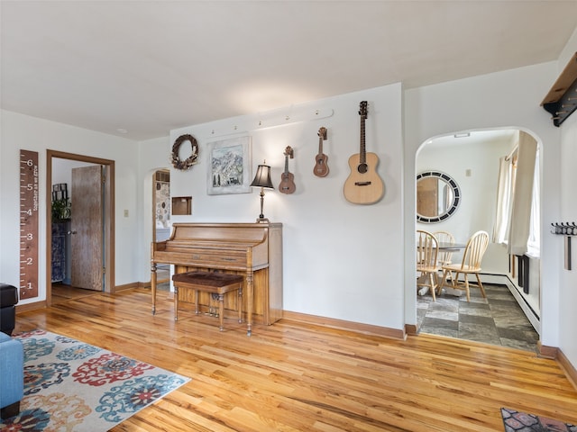 living room with arched walkways, wood finished floors, and baseboards