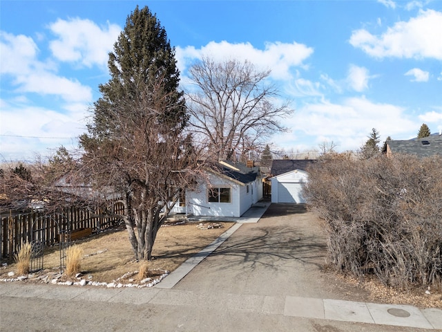 view of front facade featuring an outbuilding, aphalt driveway, and fence