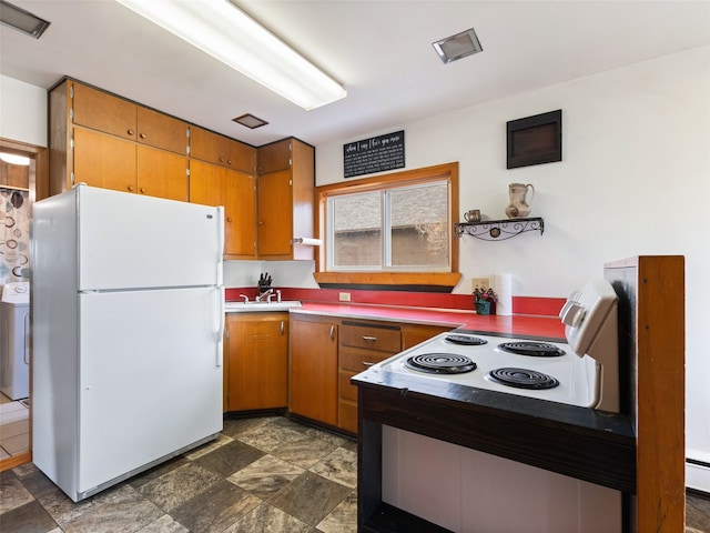 kitchen featuring washer / dryer, brown cabinetry, electric range oven, and freestanding refrigerator