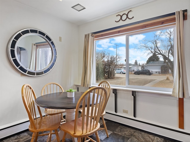 dining room featuring plenty of natural light, stone finish flooring, and a baseboard radiator