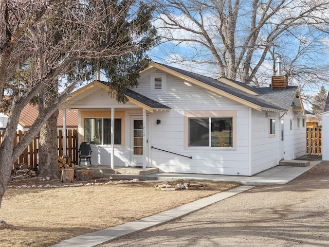 bungalow with roof with shingles, fence, and a chimney