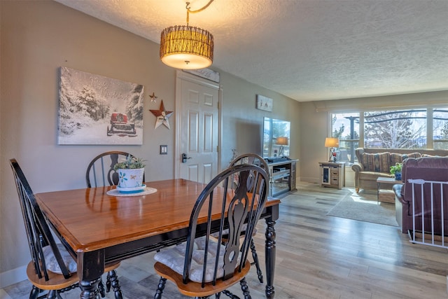 dining space featuring light wood-style flooring and a textured ceiling