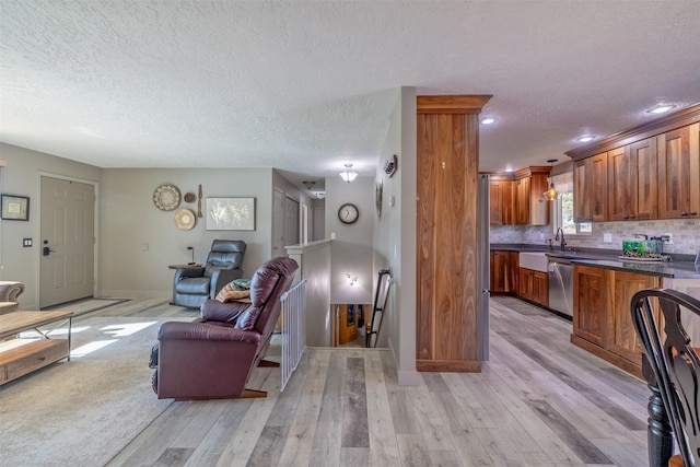 living area with light wood-style flooring, baseboards, and a textured ceiling