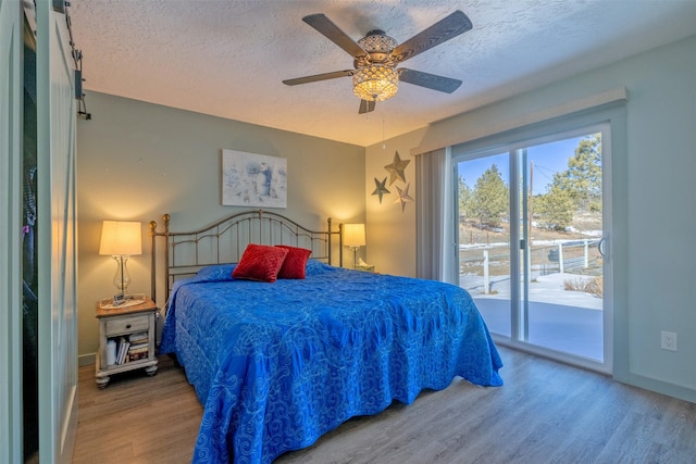 bedroom with access to outside, a textured ceiling, baseboards, and wood finished floors