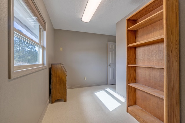 interior space featuring carpet floors, a textured ceiling, and baseboards