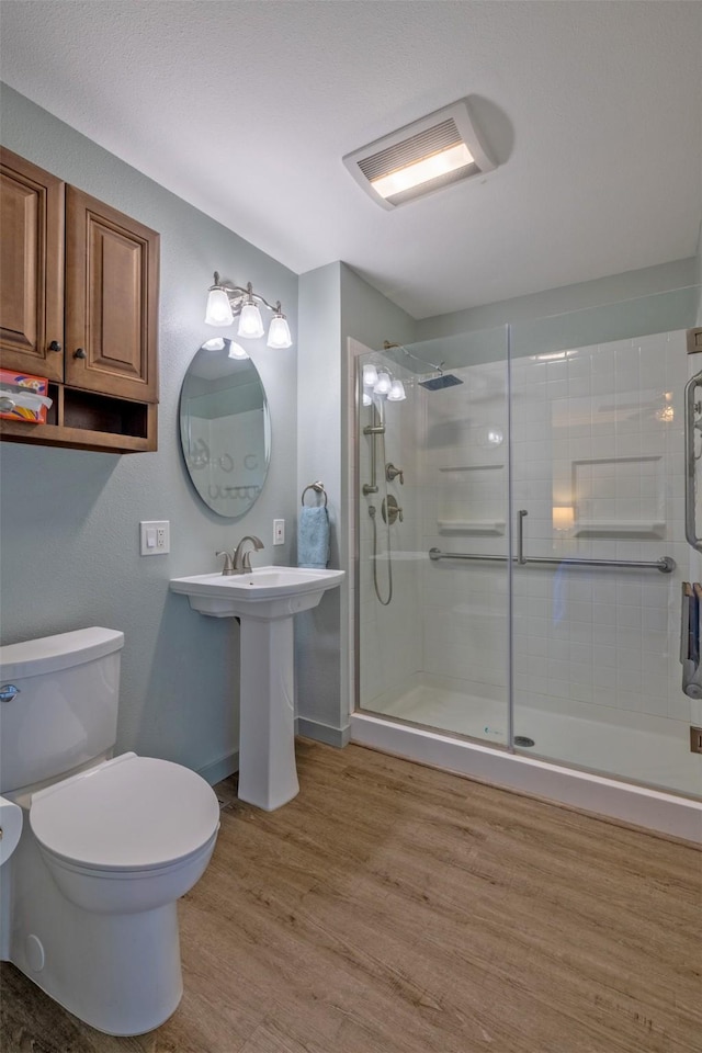 full bathroom featuring a stall shower, wood finished floors, toilet, and baseboards