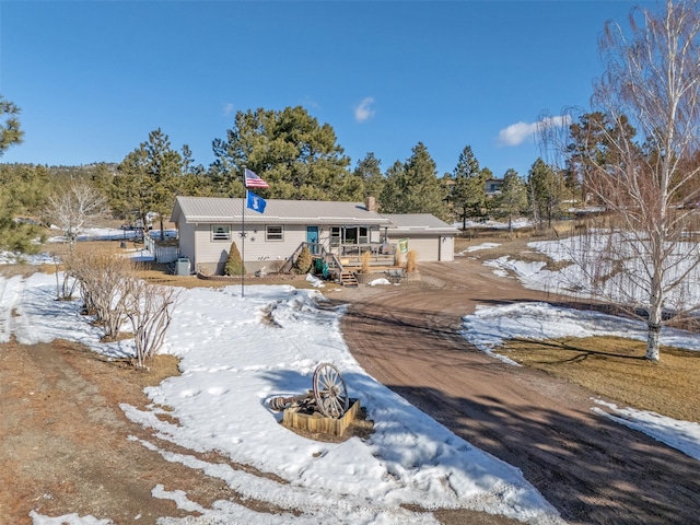 snow covered property with an outbuilding, driveway, and an attached garage