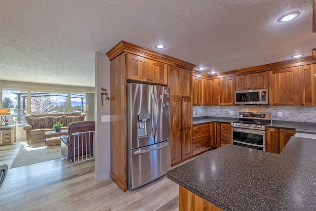 kitchen featuring appliances with stainless steel finishes, dark countertops, and brown cabinets