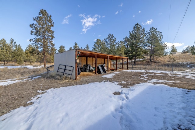 snow covered structure with an outbuilding and an outdoor structure