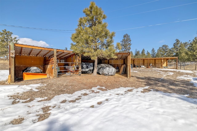 yard layered in snow with a carport, an exterior structure, and an outdoor structure