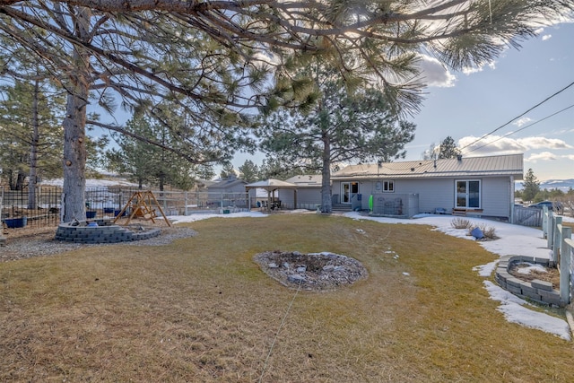 rear view of property featuring a patio, a fenced backyard, metal roof, a yard, and a playground