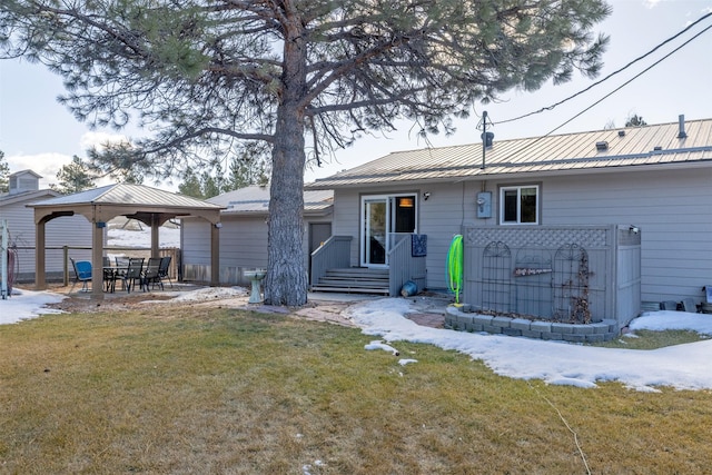 rear view of property featuring fence, metal roof, a lawn, and a gazebo