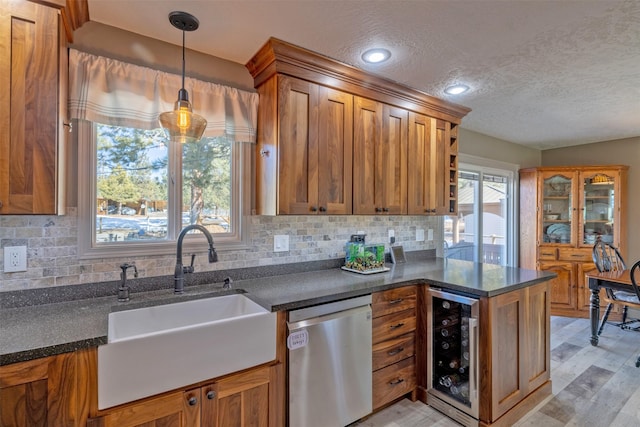 kitchen featuring stainless steel dishwasher, wine cooler, a sink, and brown cabinetry