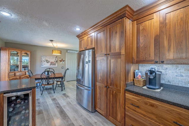 kitchen featuring wine cooler, light wood-style floors, brown cabinets, decorative backsplash, and stainless steel fridge