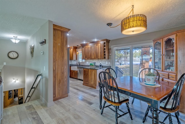 dining space with light wood-type flooring and a textured ceiling